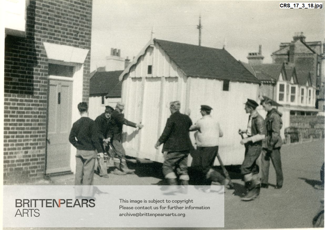 Photograph of men moving a beach hut