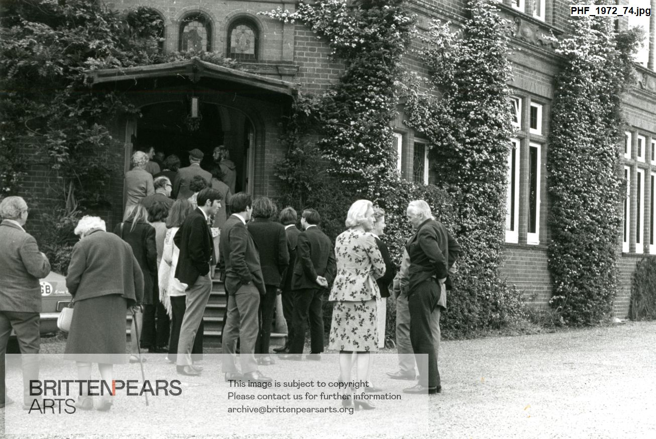 Photograph of Pat and William Servaes amongst a crowd going into a building