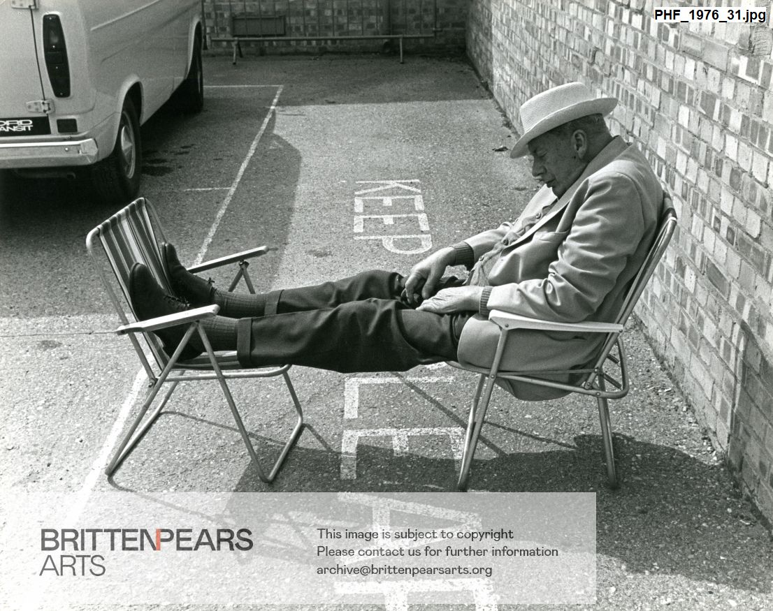 Photograph of an unidentified guest asleep on two chairs in car park