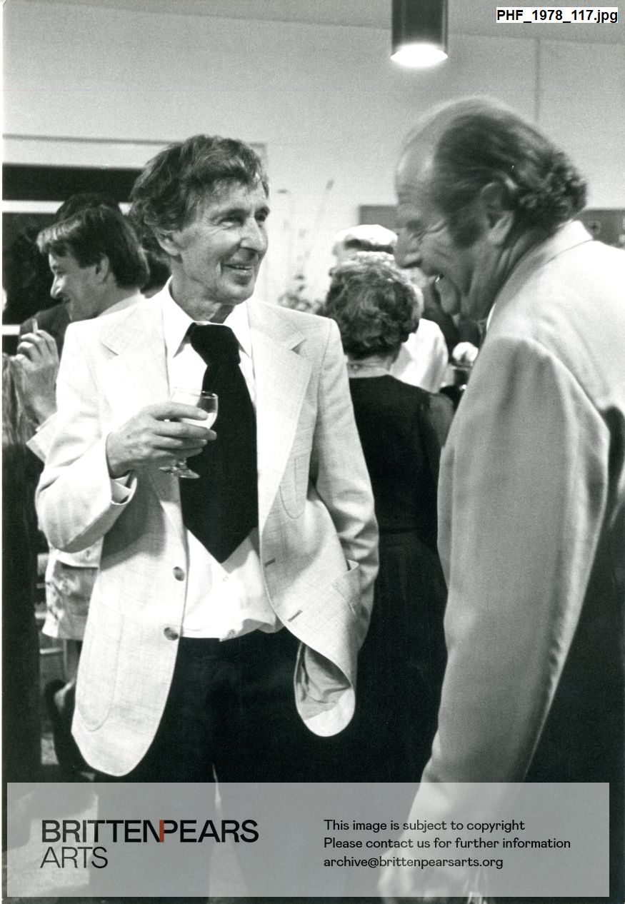 Photograph of Sir Michael Tippett talking to Norman Del Mar at a reception