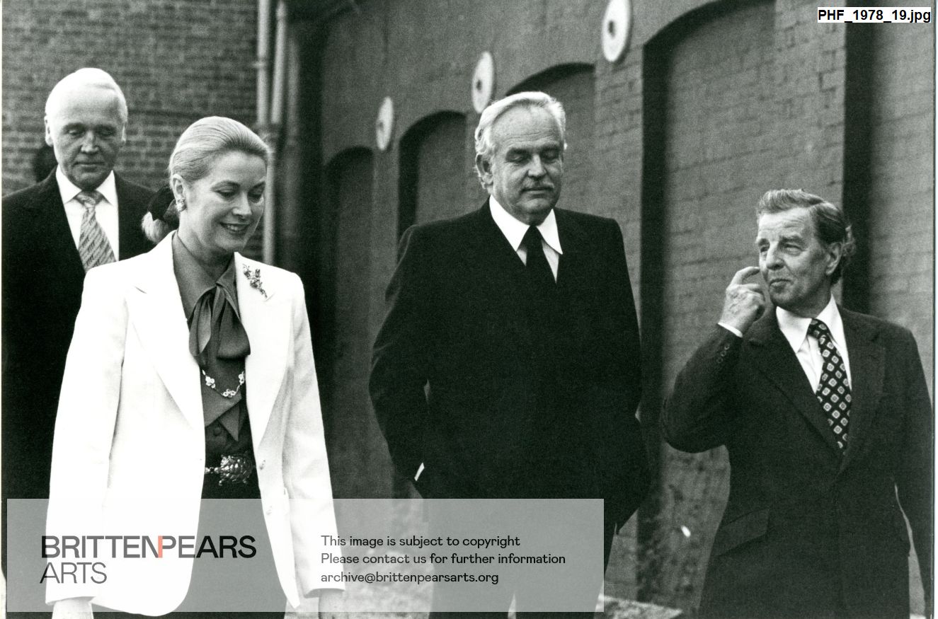 Photograph of Prince Ranier and Princess Grace of Monaco with Sir Eugene Melville and William Servaes outside the Concert Hall at Snape Maltings